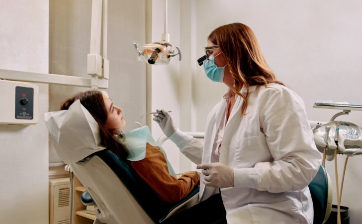 A dentist sitting chairside with a patient