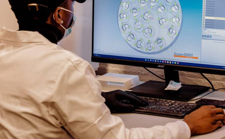 A man looking at crowns being milled digitally through CAD