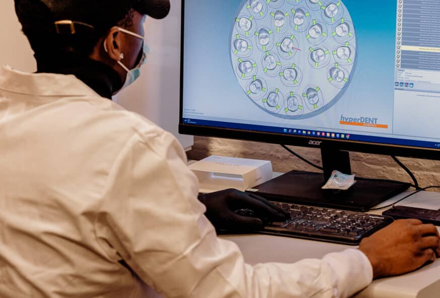 A man looking at crowns being milled digitally through CAD