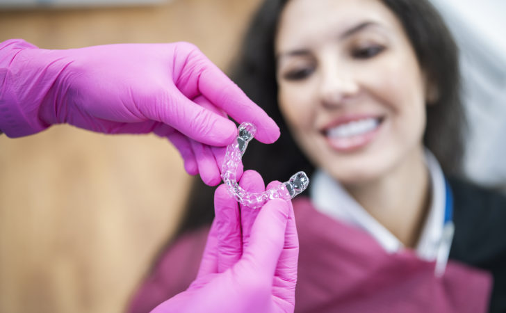 Orthodontist giving a happy patient dental aligners.