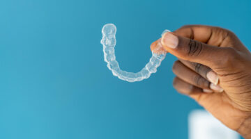 photo of clear aligner being held in front of a blue background